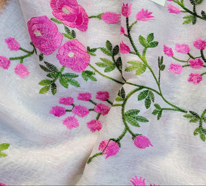 Embroidered fabric with pink flowers and green leaves, featuring a brand tag.