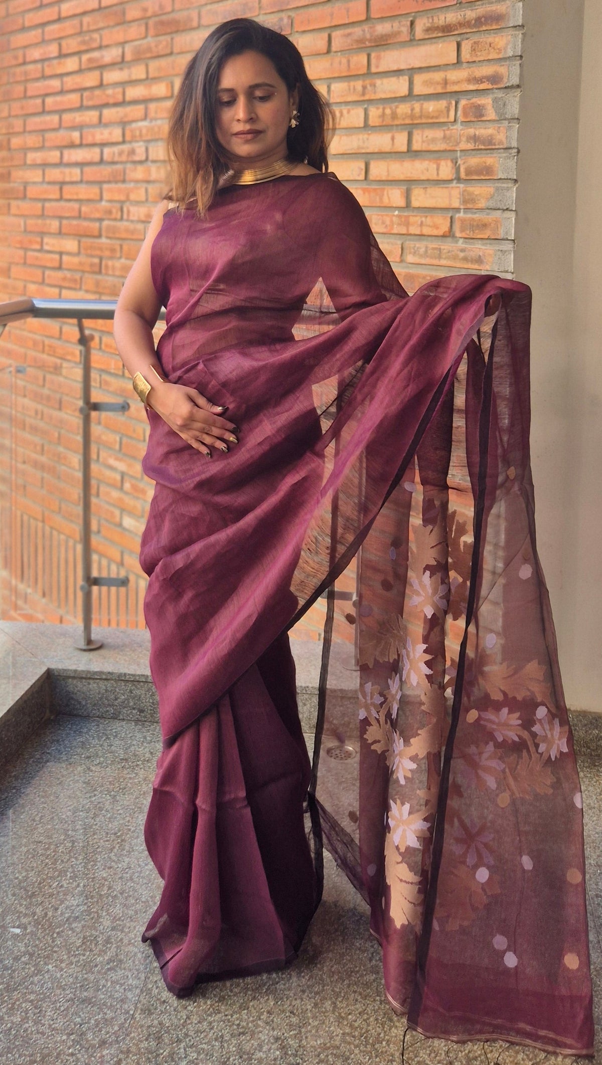 Person wearing a burgundy dress standing outside a building with a brick wall.
