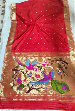 Red saree with floral and bird embroidery on a patterned fabric background