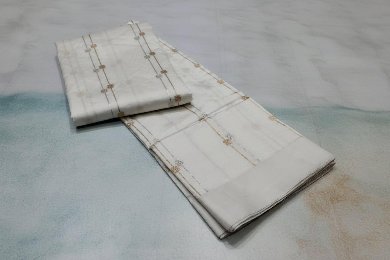 Folded fabric with gold embroidery on a reflective surface