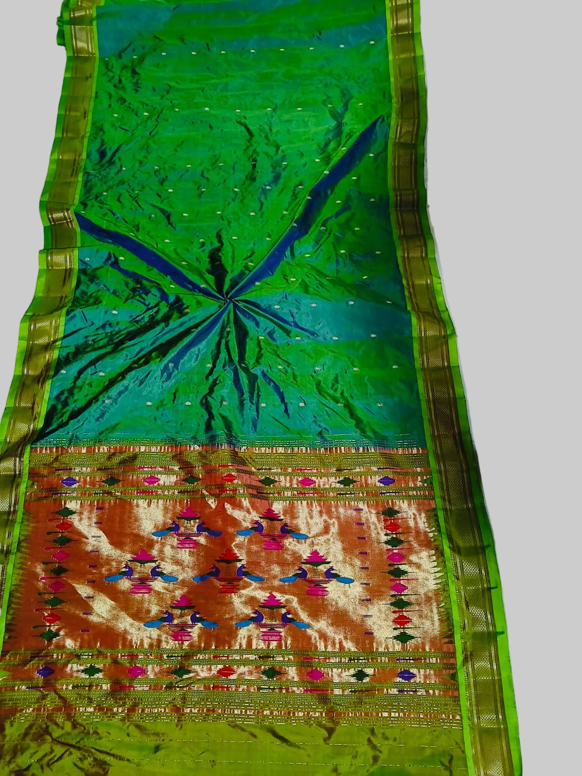 Traditional saree with green and orange patterns on a white background